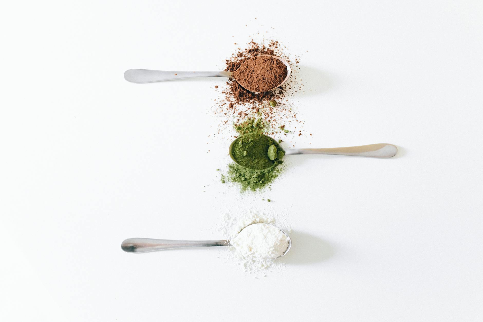 Close-Up Shot of Spoons with Colored Powders on a White Surface